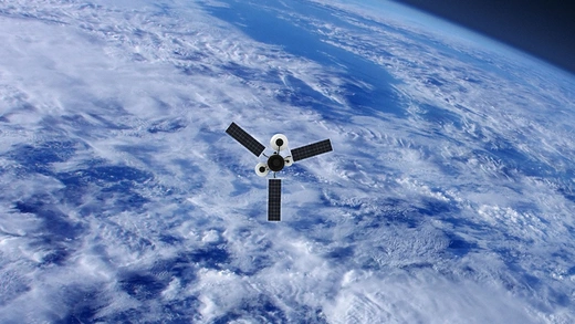 A satellite with three extended solar panels passes over a cloudy ocean while orbiting Earth. 
