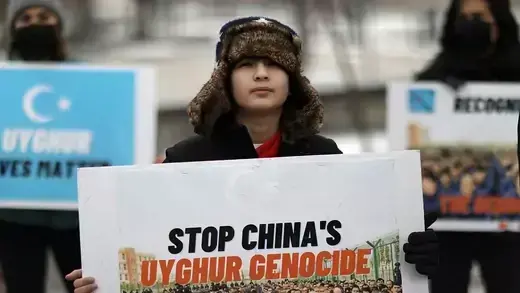 A boy holds a sign that reads "Stop China's Uyghur Genocide." 