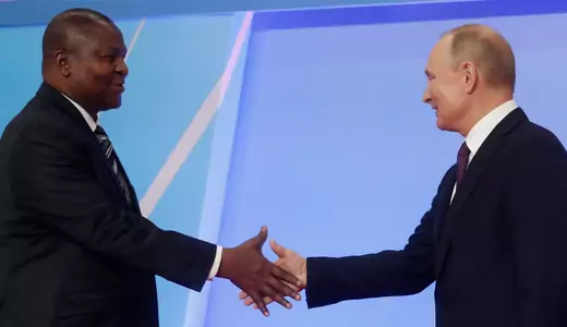 Russian President Vladimir Putin and President Faustin Archange Touadera of the Central African Republic walk towards each other, arms outstretched as they prepare to shake hands.