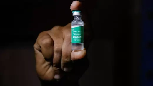 A hand holds a vial of the COVID-19 vaccine