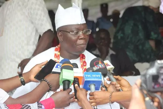 A picture of the Aare Ona Kakanfo of Yorubaland, Gani Adams, being interviewed. A collection of microphones have been thrust by reporters in front of him.