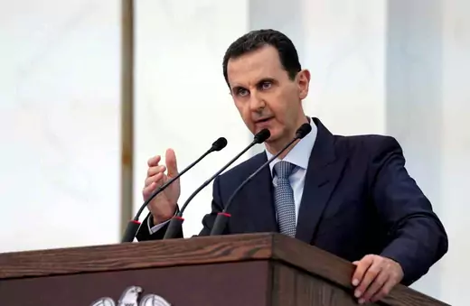 Syrian President Bashar al-Assad speaks at a lectern