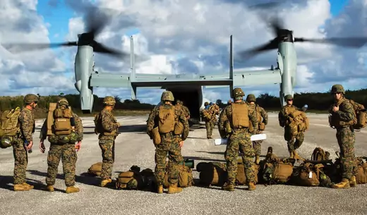 U.S. Marines stand ready to board an Osprey military aircraft.