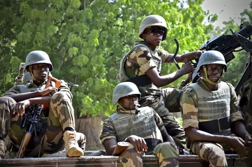 Several Nigerien soldiers are seen seated on a truck wearing military gear.