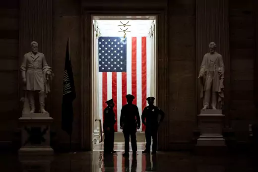U.S. Capitol Police officers stand in front of an American flag in the Rotunda of the U.S. Capitol in Washington, DC.