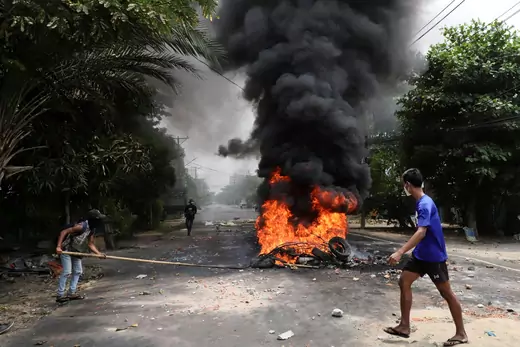An anti-coup protester walks past burning tires after activists launched a "garbage strike" against the military rule, in Yangon, Myanmar on March 30, 2021.