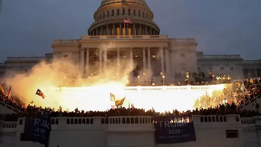 Supporters of U.S. President Donald Trump stand in front of the Capitol Building as its lit on fire.
