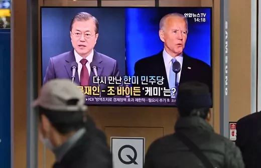 People watch a television news programme reporting on the US presidential election showing images of US President-elect Joe Biden (R) and South Korean President Moon Jae-in (L), at a railway station in Seoul on November 9, 2020.