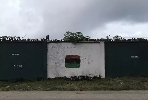 A wall is seen with a flag of the former breakaway Republic of Biafra; the flag is made up of three horizontal colored bars. From top: red, black, and green.