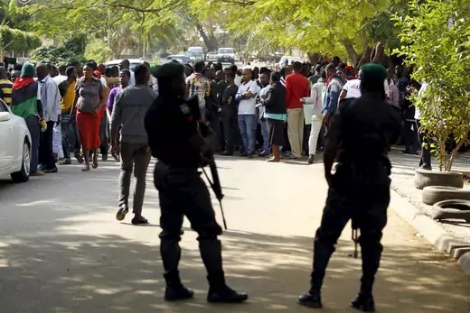 Soldiers, seen mostly as silhouettes, watch a group of protesters in Nigeria.