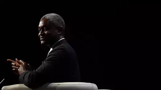 President and Chief Executive Officer of the Federal Reserve Bank of Atlanta Raphael W. Bostic sitting on a white couch facing left against a black background