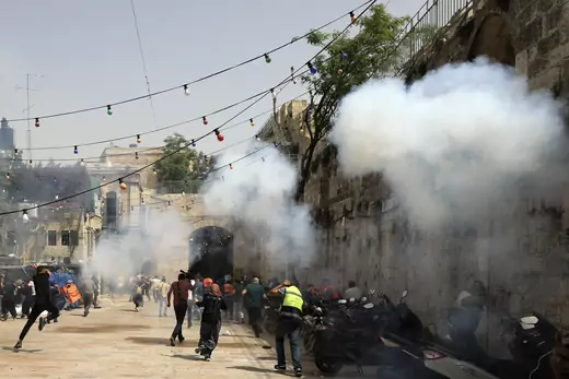 Palestinians run away as Israeli police fire a stun grenade during clashes at the compound that houses Al-Aqsa Mosque, known to Muslims as Noble Sanctuary and to Jews as Temple Mount, in Jerusalem's Old City, May 10, 2021.
