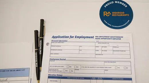 An employment application form and black pens on a white table.