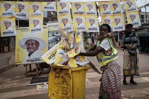 A worker throws away campaign posters of President Yoweri Museveni after Uganda’s 2021 election.