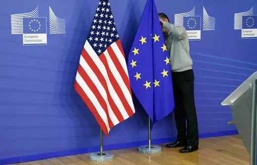 A worker adjusts European Union and U.S. flags at the start of the 2nd round of EU-US trade negotiations for Transatlantic Trade and Investment Partnership at the EU Commission headquarters in Brussels November 11, 2013.
