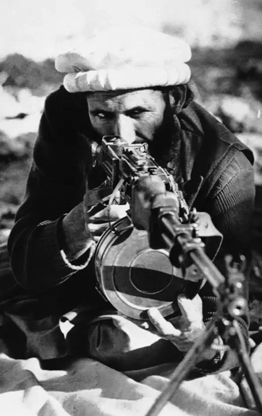 An Afghan tribal rebel poses for a photographer behind the sights of a Soviet-made light machine gun.