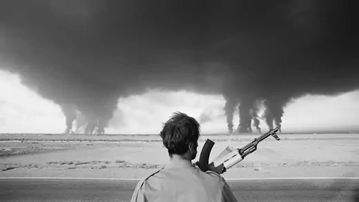 An Iraqi soldier watches as the Iranian Abadan refinery burns.