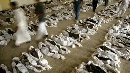 Iraqis walk between hundreds of bodies found in a mass grave.