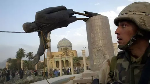 A U.S. Marine watches as a statue of Iraq's President Saddam Hussein falls.
