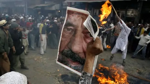 A Muslim protester holds a picture of slain former Iraqi President Saddam Hussein as others burn an effigy of U.S. President George Bush.