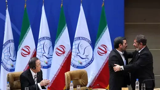 Egyptian President Mohamed Morsi (R) embraces his Iranian counterpart Mahmoud Ahmadinejad (C) as UN Secretary General Ban Ki-Moon (L) applauds.