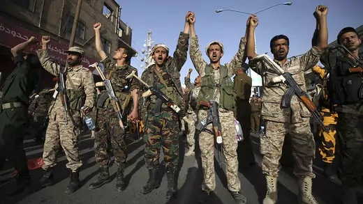 Houthi fighters in army uniform shout slogans during a demonstration.