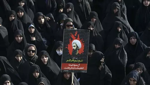 An Iranian woman holds up a poster showing Sheikh Nimr al-Nimr, a prominent opposition Saudi Shiite cleric who was executed by Saudi Arabia