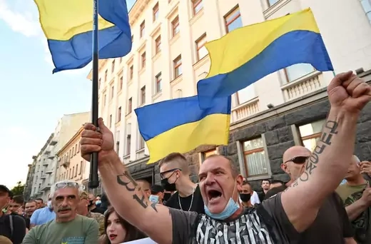 Demonstrators wave Ukrainian flags during a rally outside the President's office organised by opposition parties and movements to demand his impeachment for high treason, in Kiev on June 28, 2021.
