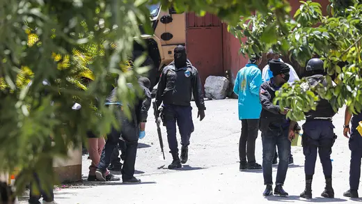 A photo of security and police personnel congregating. In the foreground, tree limbs frame the image.