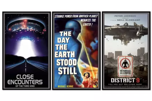 Movie posters in black frames. From left: Close Encounters of the Third Kind (a UFO shines a beams light onto a dark road); The Day the Earth Stood Still (a robot shoots a laser toward the U.S. Capitol Building as a woman screams); and District 9 (a sign in the foreground reads, "No Humans Allowed," as a spaceship hovers over a slum in the background).