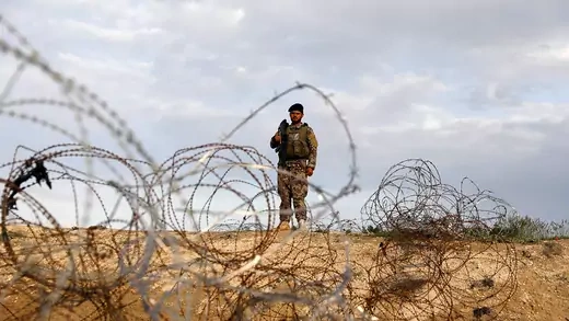 An Afghan army soldier stands next to a heap of barbed wire.