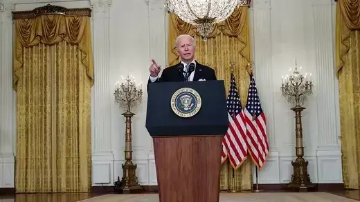 Joe Biden stands behind a podium in the White House.