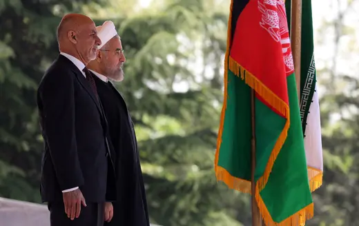 Afghan President Mohammad Ashraf Ghani and Iranian President Hassan Rouhani face the Iranian and Afghan flags