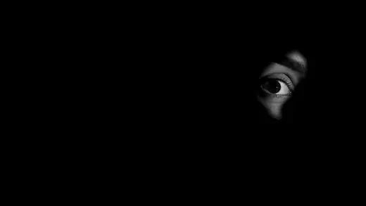 Eye of a person seen through darkness and shadows