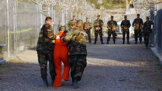 U.S. military police escort a detainee to his cell in Camp X-Ray at Guantanamo Bay in January 2002. 