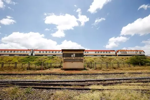 An SGR passenger train travels past the town of Sultan Hamud, Kenya, in front of a blue sky with clouds on February 13, 2019. 