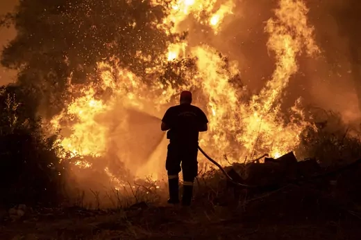 A firefighter tries to extinguish a wildfire burning in the village of Pefki, on the island of Evia, Greece, August 8, 2021.