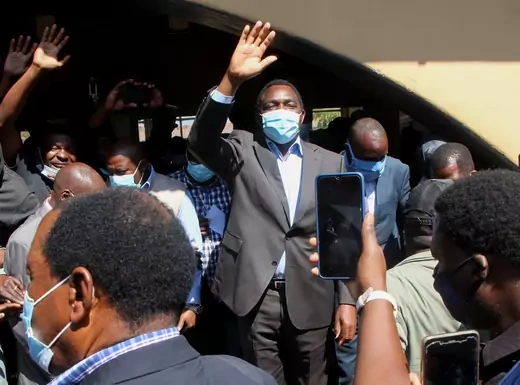 Hakainde Hichilema, Zambian opposition leader, waves to his supporters while wearing a mask.