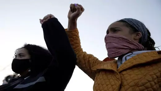 Two women with raised fists calling for racial justice.
