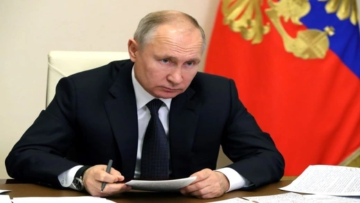 Putin sitting at a meeting.