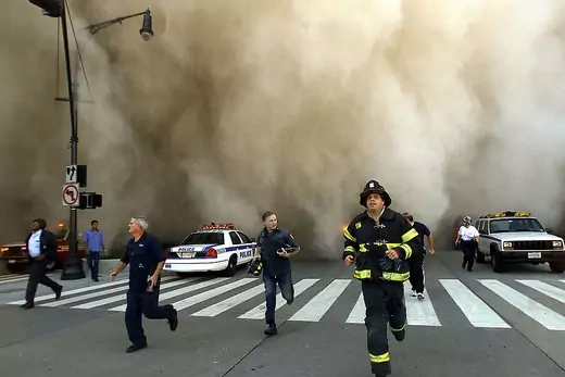 Policemen and firemen run away from the huge dust cloud caused as the World Trade Center's Tower One collapses after terrorists crashed two hijacked planes into the twin towers, September 11, 2001 in New York City.