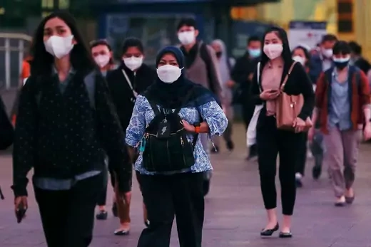 People wearing protective face masks walk on a road during rush hour as the government extends restrictions to curb the spread of coronavirus disease (COVID-19) in Jakarta, Indonesia.