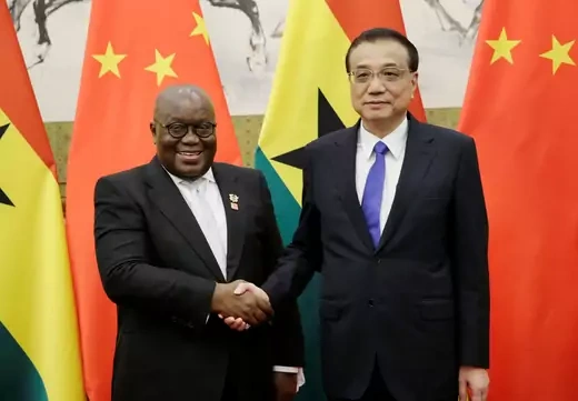 Ghanian President Nana Akufo-Addo shakes hands with Chinese Premier Li Keqiang, in front of Chinese and Ghanian flags.