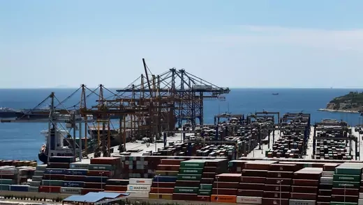 View of Piraeus Port in Greece shows cargo containers and the ocean behind.