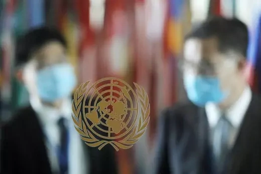 People in masks arrive behind the emblem of the United Nations at its headquarters, as the General Assembly appointed Secretary-General Antonio Guterres for a second five-year term from January 1, 2022, in New York City, New York, U.S., June 18, 2021.