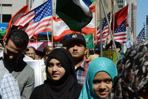 Men and women at New York's Muslim Day parade stand in front of flags of the U.S. and some Muslim-majority countries
