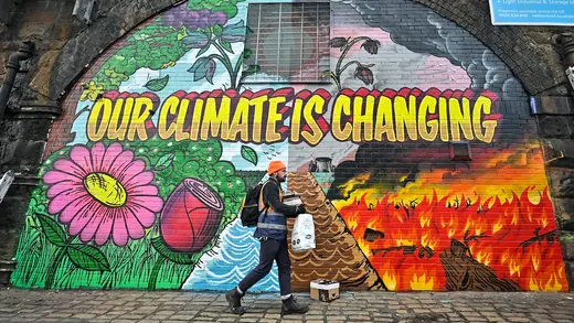 A person paints a mural that reads, "Our Climate Is Changing."