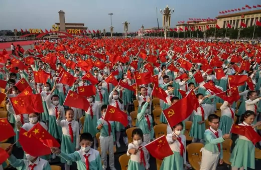 Chinese students wave party and national flags at a ceremony marking the 100th anniversary of the Communist Party at Tiananmen Square on July 1, 2021 in Beijing, China.