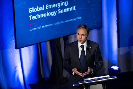 U.S. Secretary of State Antony Blinken speaking at a podium in front of a sign that reads "Global Emerging Technology Summit: Advancing Prosperity, Security, and Innovation"