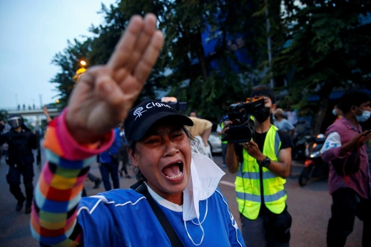 Protestor in Thailand holds up three fingers while chanting.